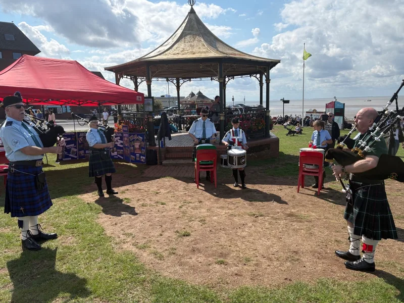 Pipers and drummers playing beside a seafront bandstand