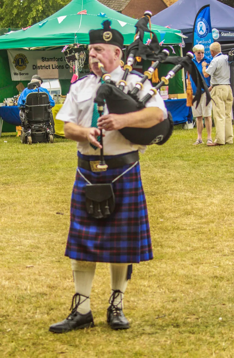 A Bomber County piper playing the bagpipes on a showground field