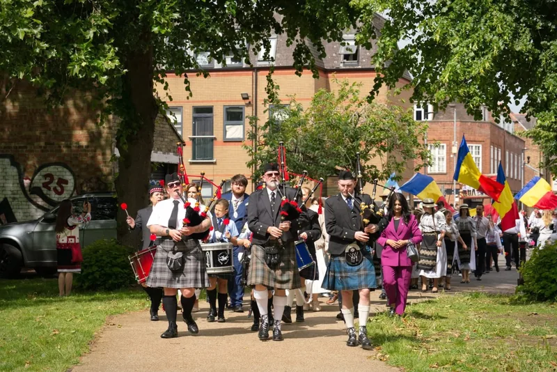 The band marching in a street procession with international flags