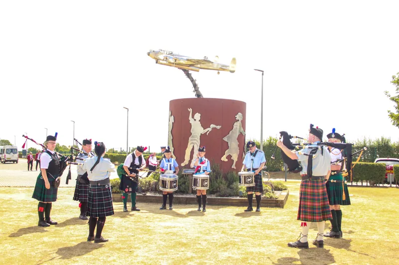The band playing beside an aviation memorial topped with an aircraft sculpture